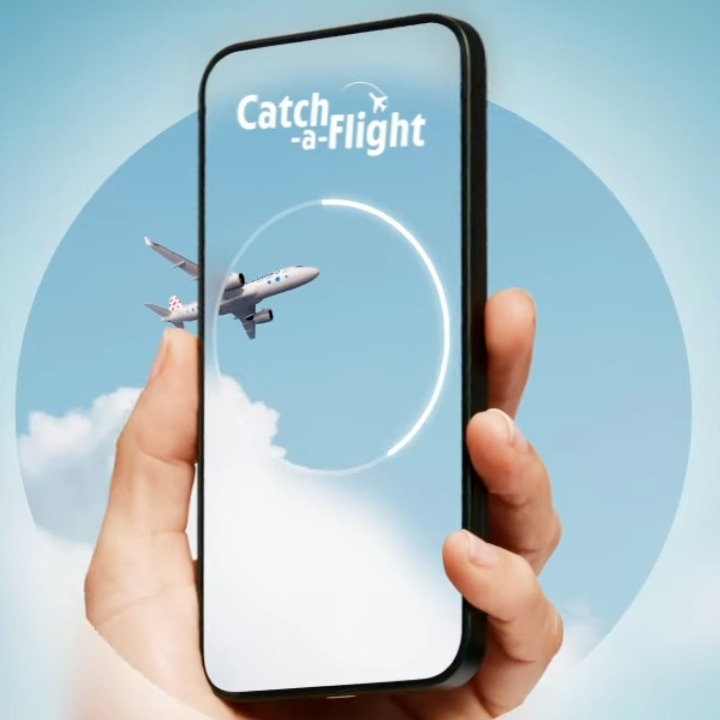 Una mano sostiene un móvil mientras un avión cruza la pantalla