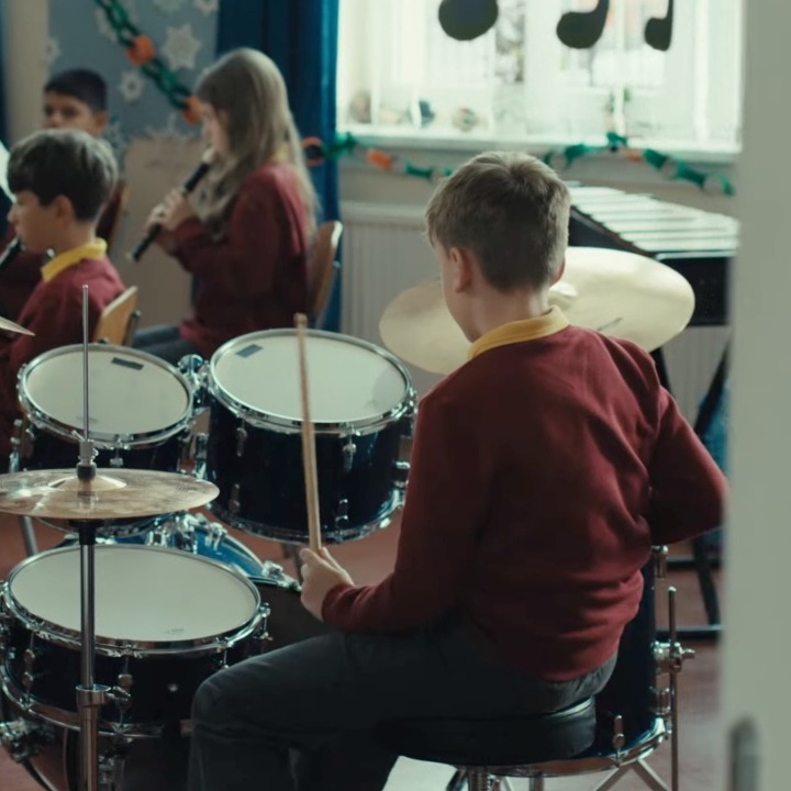 Un niño tocando la batería en una orquesta escolar