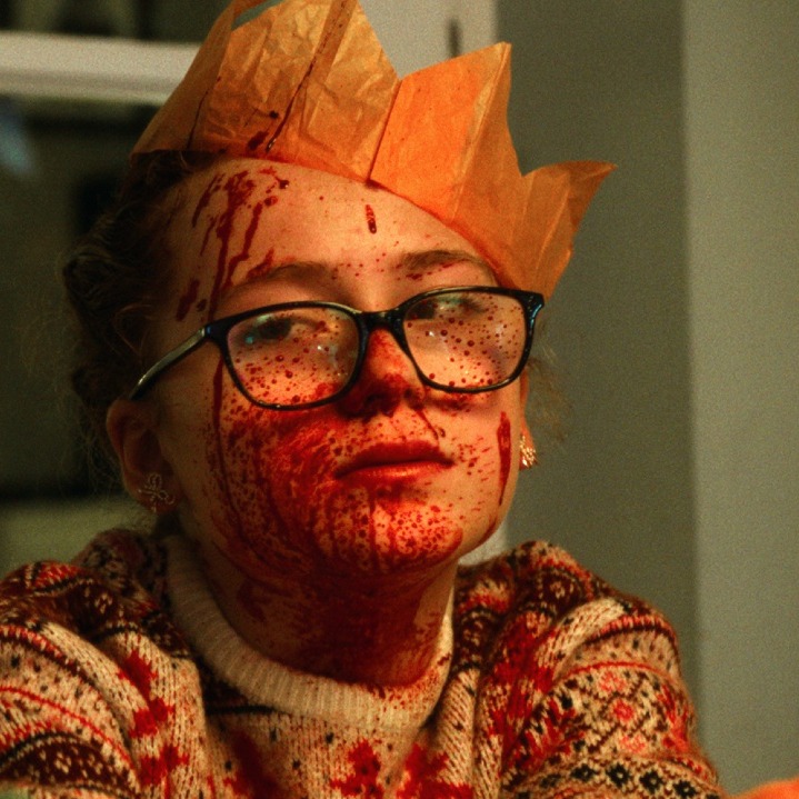 Una niña con corona de rey mago y la cara llena de sangre