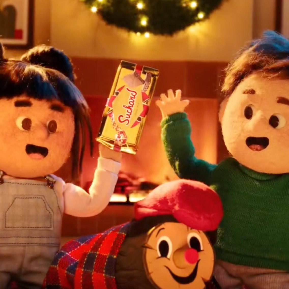 Dos niños celebrando la Navidad con una tableta de Suchard en la mano