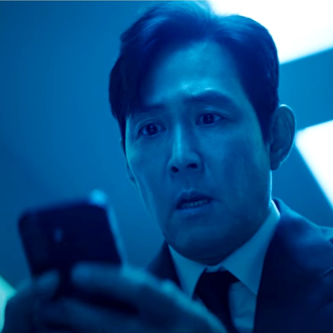 El actor Lee Jung-jae de "El juego del calamar" sujetando un móvil con cara de preocupación