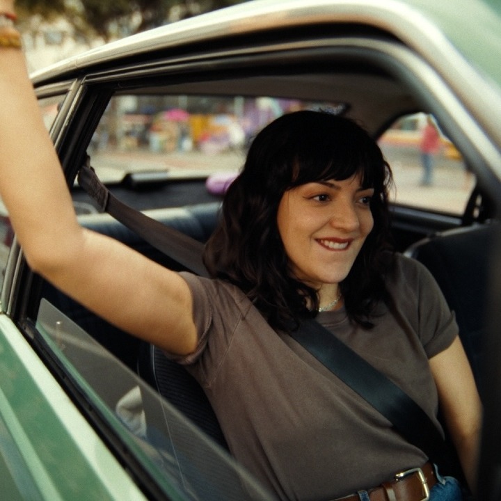 Una mujer levanta el brazo por la ventanilla mientras conduce