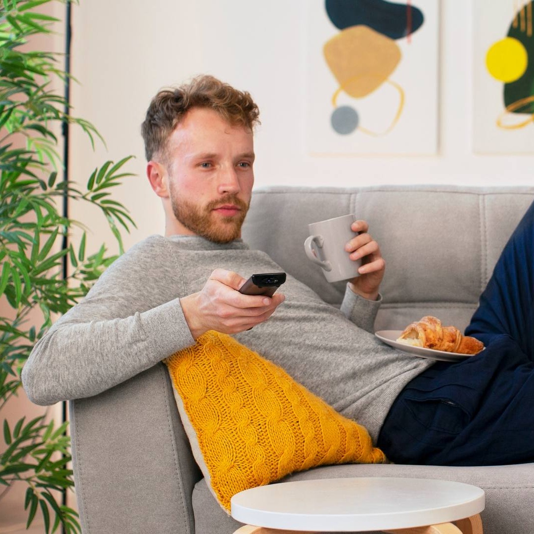 Hombre viendo la televisión tumbado en el sofá
