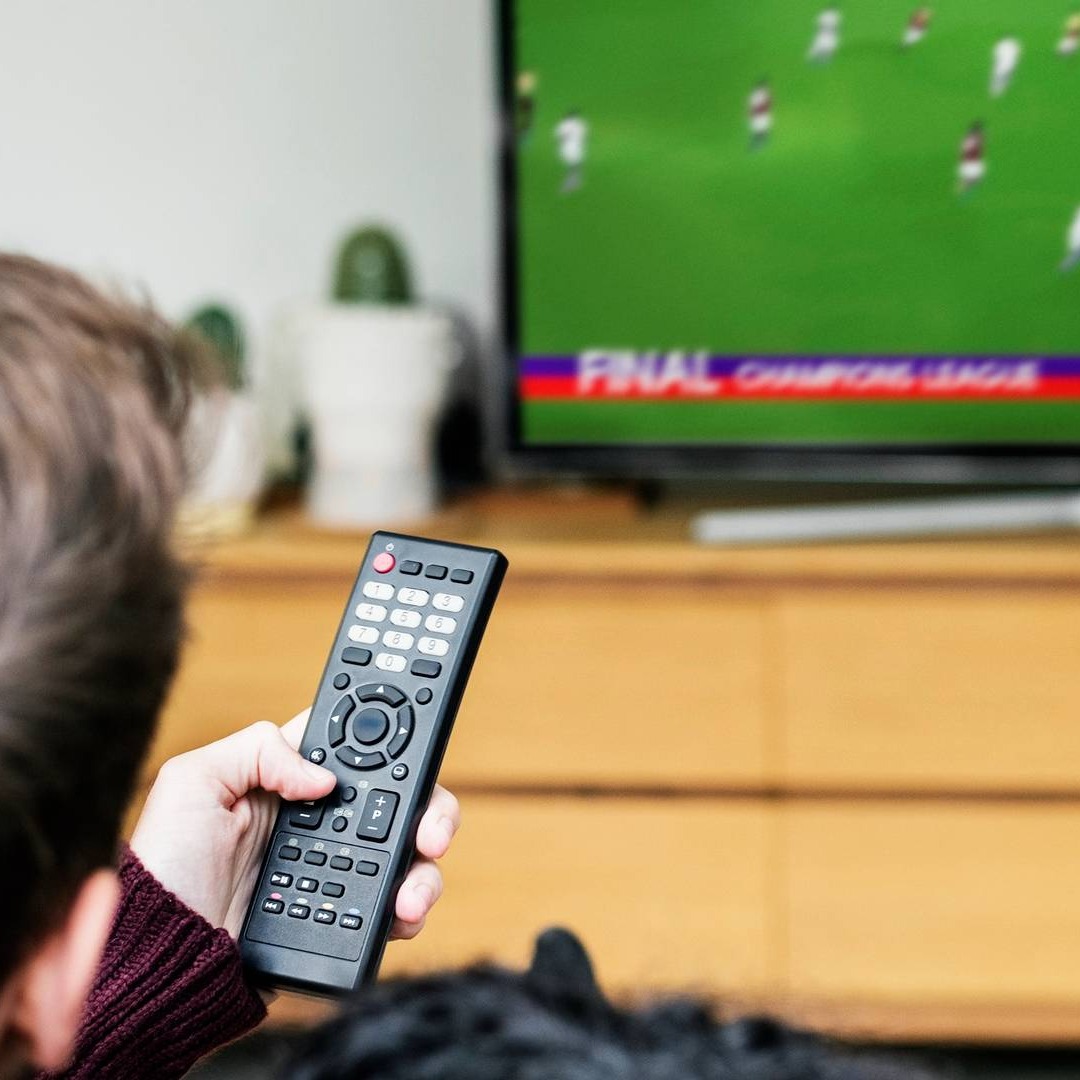 Hombre con mando a distancia en la mano viendo fútbol en televisión