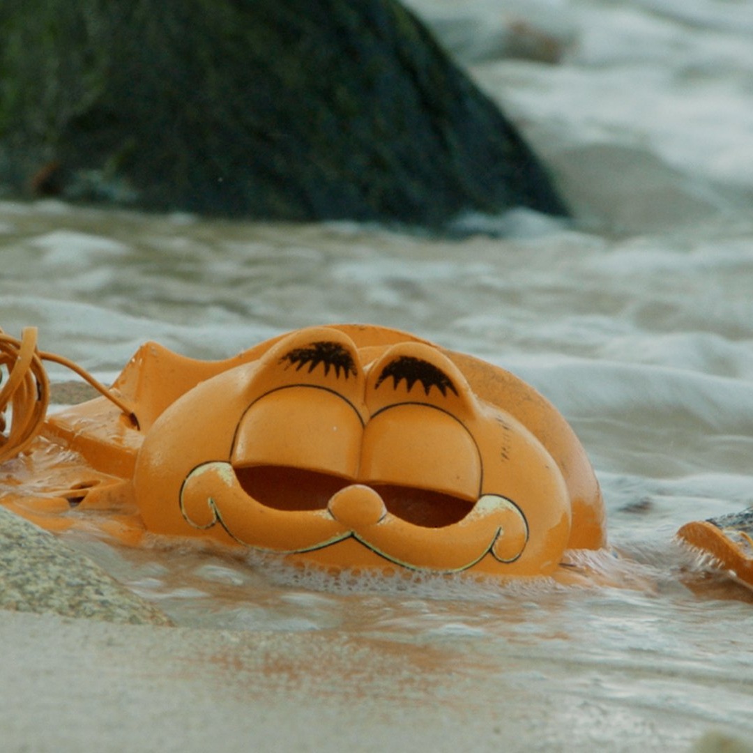 Partes de un teléfono con forma de Garfield en la playa