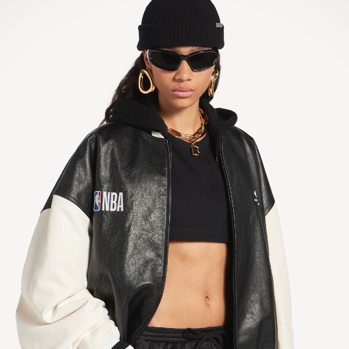 Una chica vestida con gorro de lana, gafas de sol y una cazadora de la colección con la NBA