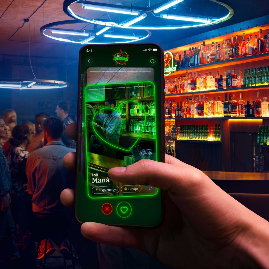 Nueva aplicación de Heineken para encontrar bares como si fueran citas románticas. Mano sosteniendo móvil en un bar