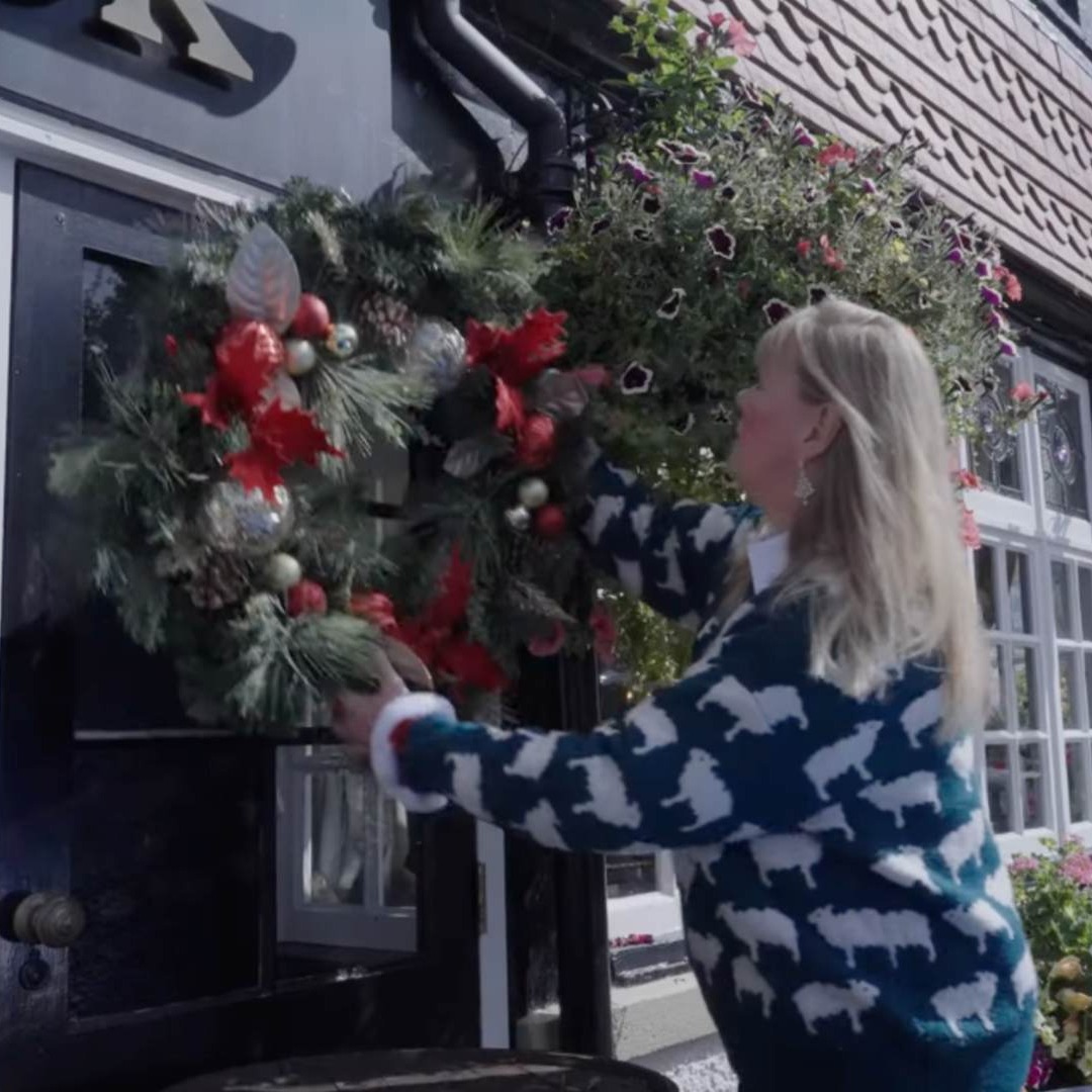 Mujer decorando su casa con una corona de Navidad