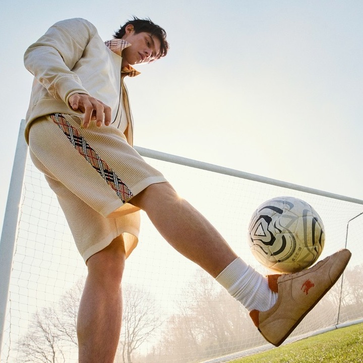 Un chico vestido de Burberry junto a una portería de fútbol dando un toque al balón