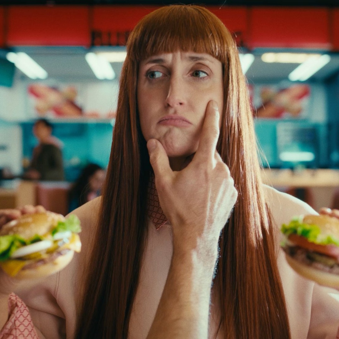 Una mujer sostiene una hamburguesa mini en cada mano