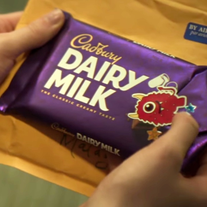 Unas manos que sostienen la tableta de Cadbury usada y cerrada con una pegatina