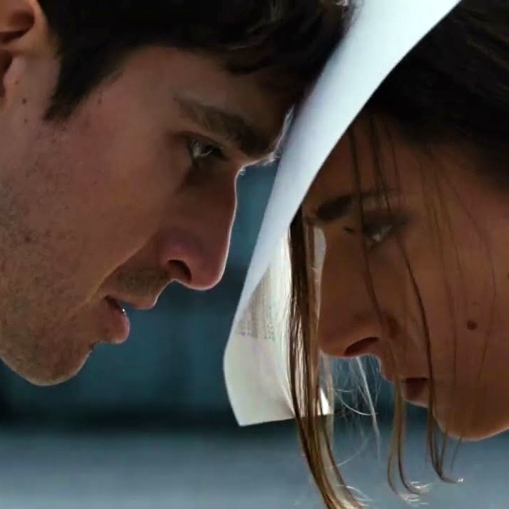 Un hombre y una mujer juntando la frente con un folio de papel entre ambos