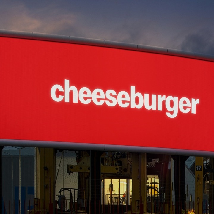 Una valla de publicidad con fondo rojo y escrito cheeseburger en blanco