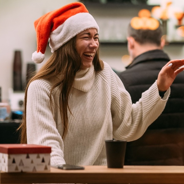 dos chicas tomando café y riendo con gorros de papá noel