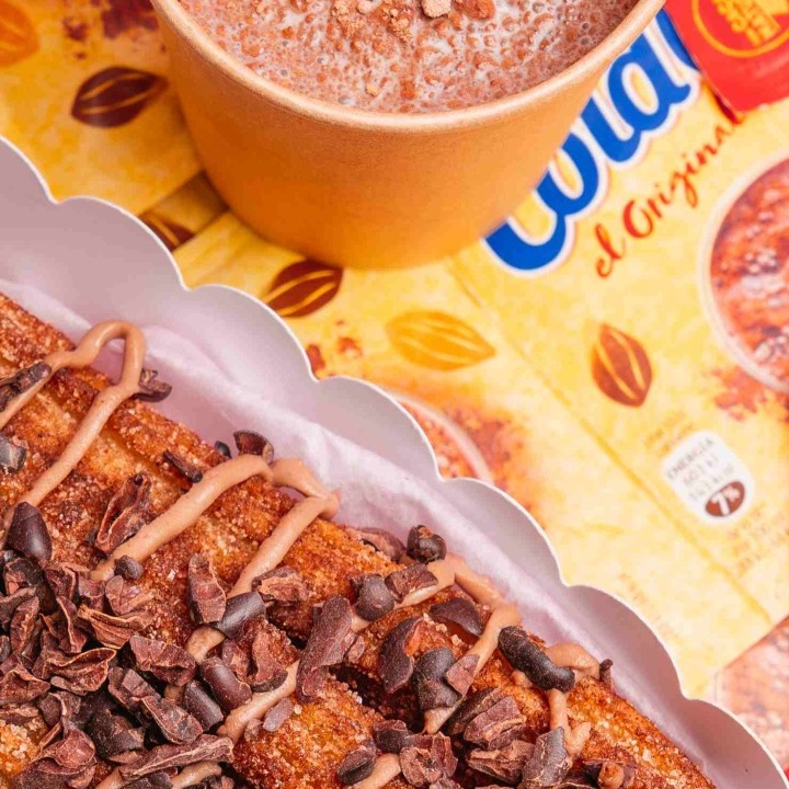 Un bodegón de churros con un vaso de ColaCao