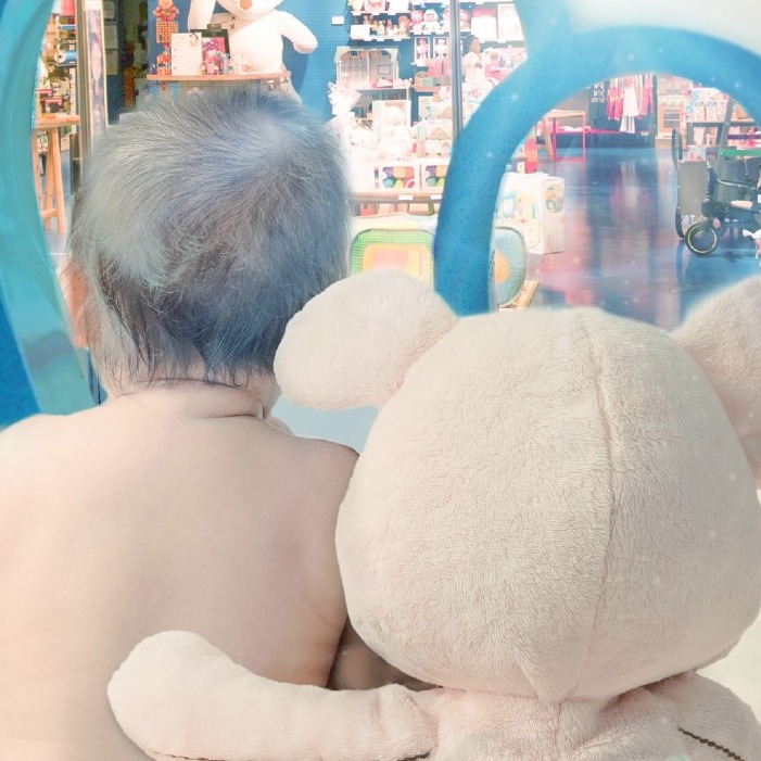 un muñeco de peluche abraza por la espalda a un bebé