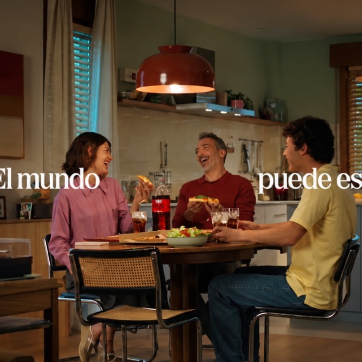 Un padre y sus dos hijos sentados a la mesa comiendo pizza y riendo
