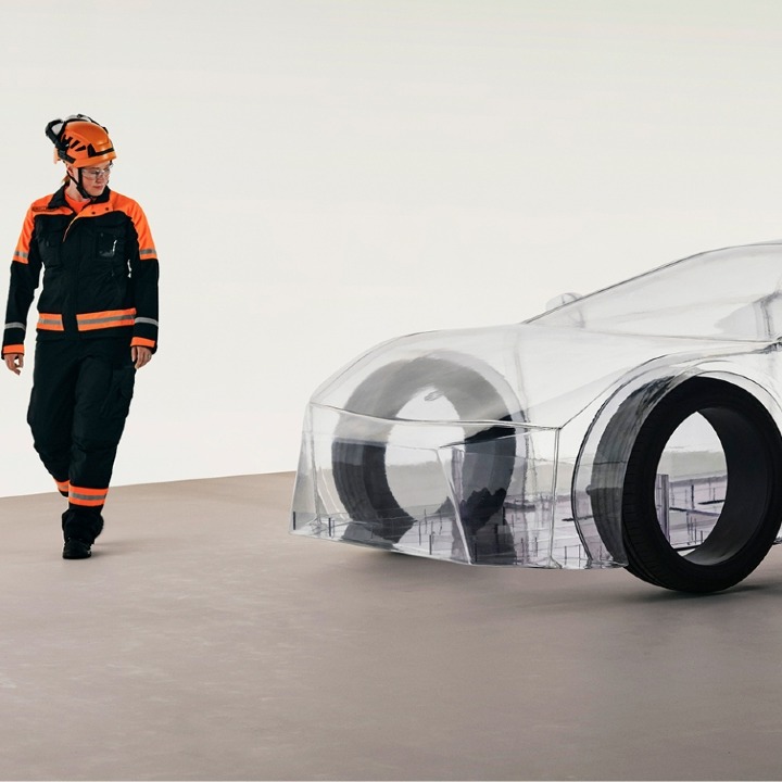 Un ingeniero pasa al lado del coche transparente al que solo se le ven las cuatro ruedas negras