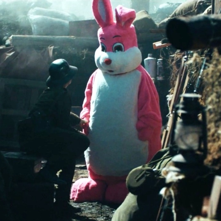 Un conejo rosa, como el de Duracell, en una trinchera bélica con soldados y armas