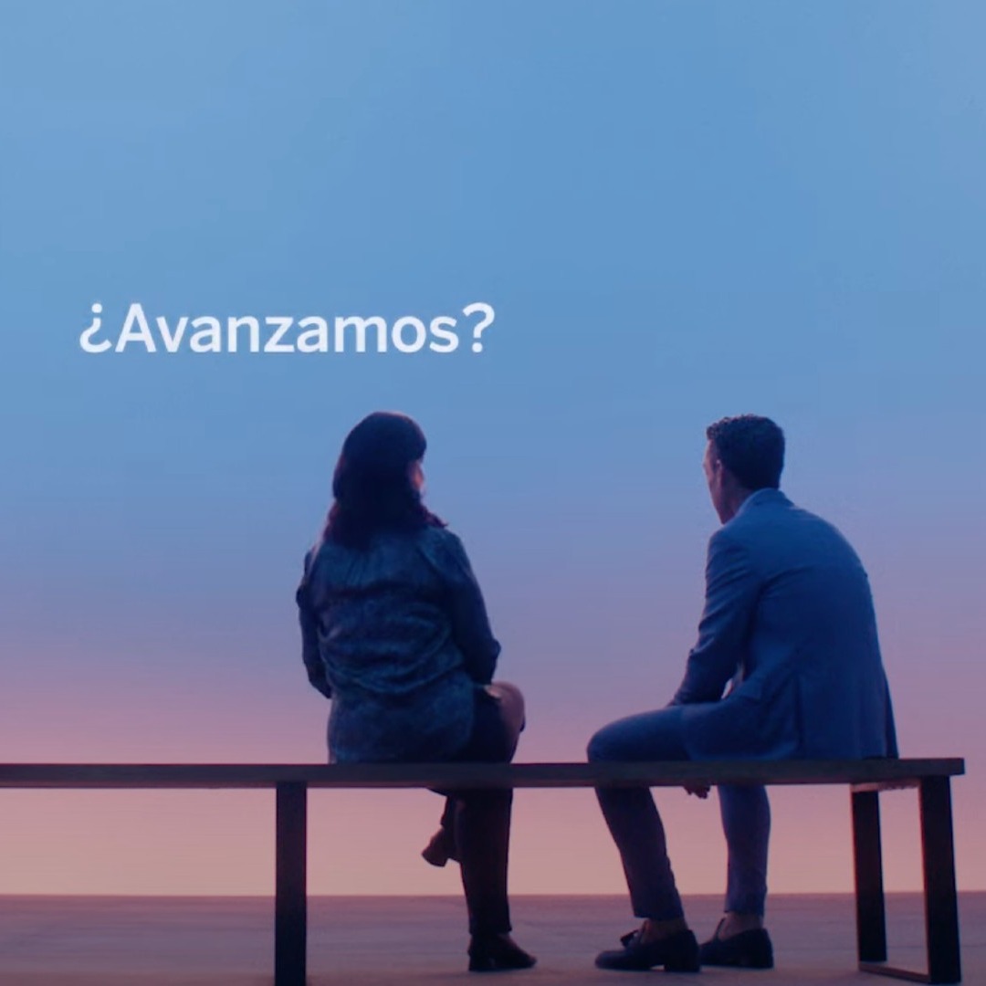 Imagen de dos personas sentadas en un banco con fondo azul