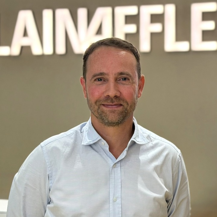 Un plano medio de Jon Mielgo y el logotipo de Alain Afflelou detrás