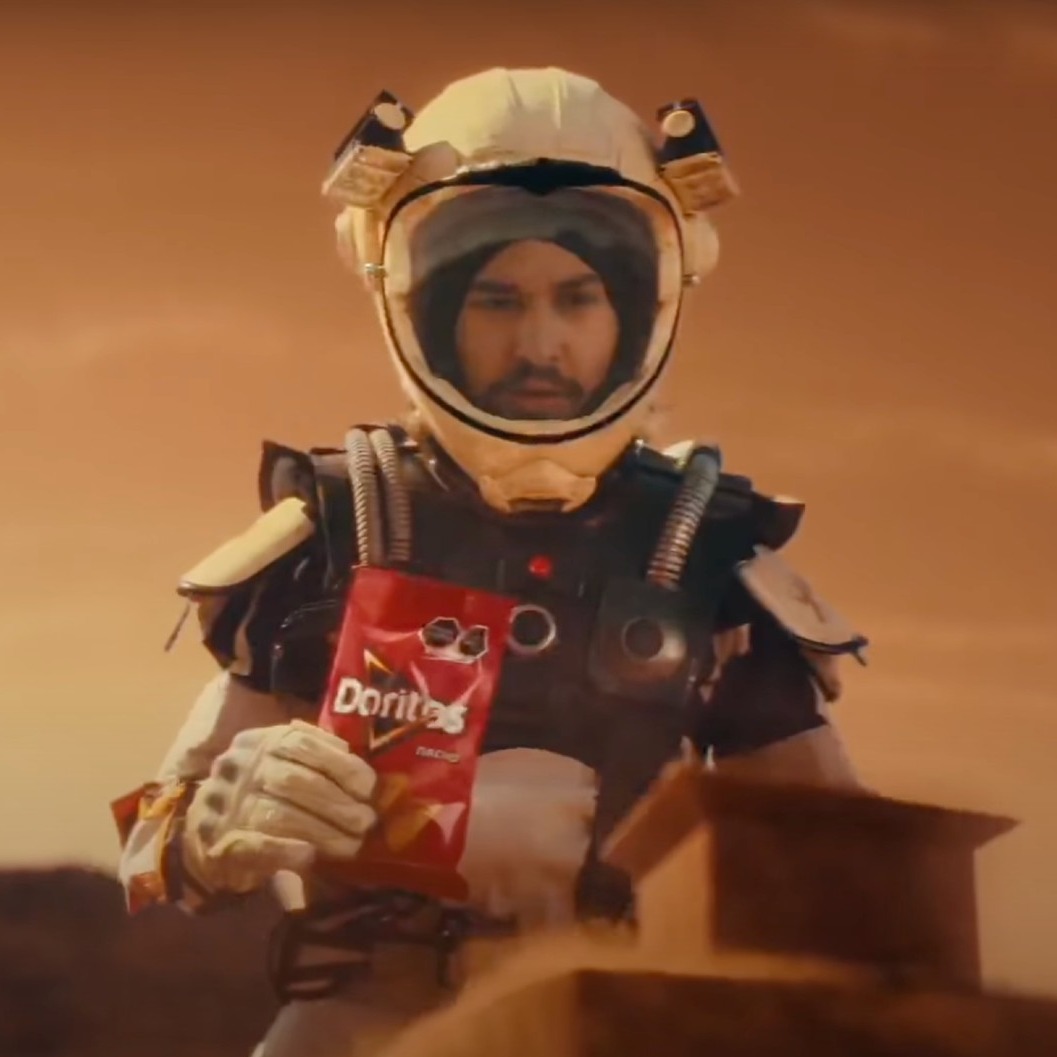 Persona disfrazada de astronauta con una bolsa de Doritos en la mano