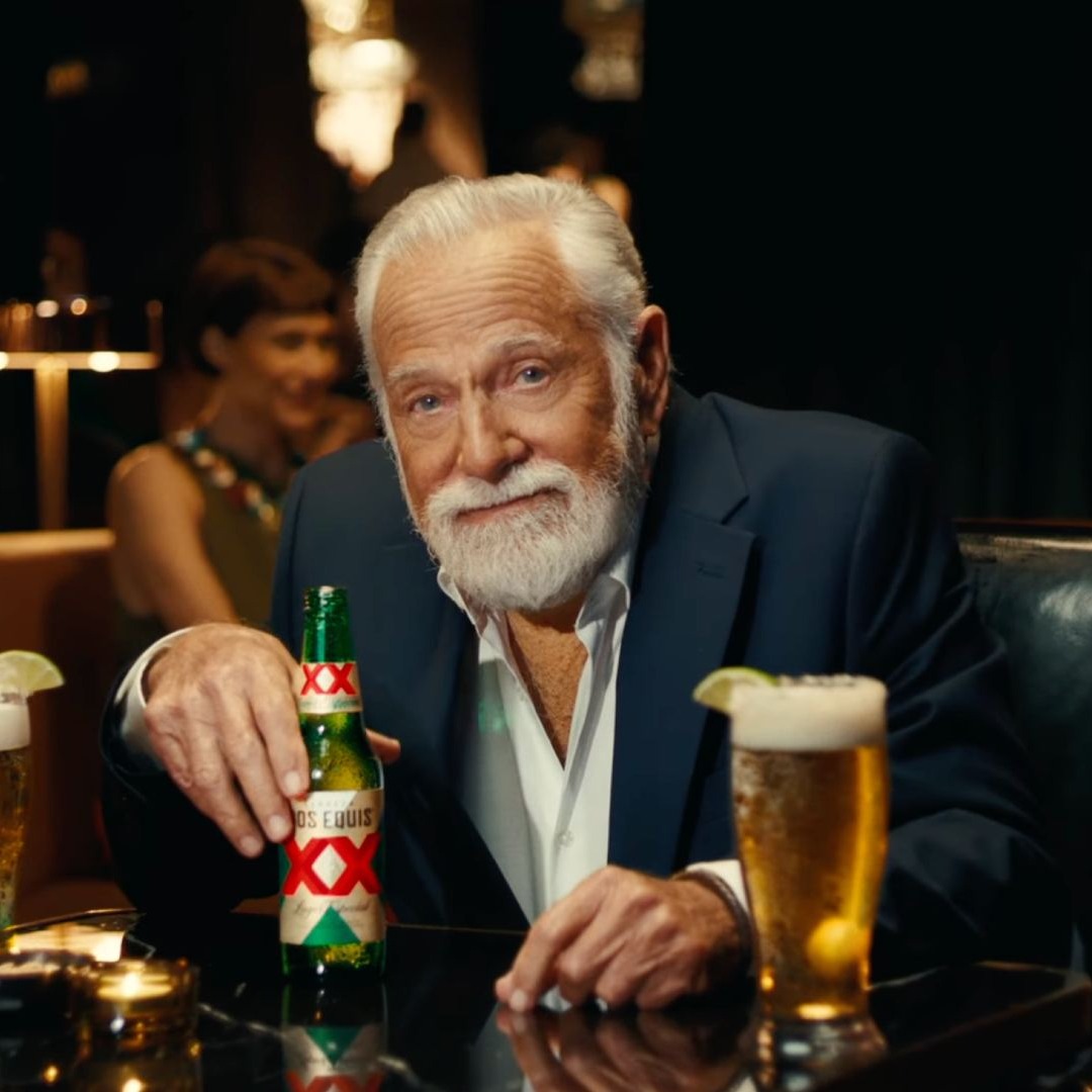 Hombre con barba blanca bebe cerveza Dos Equis en un bar