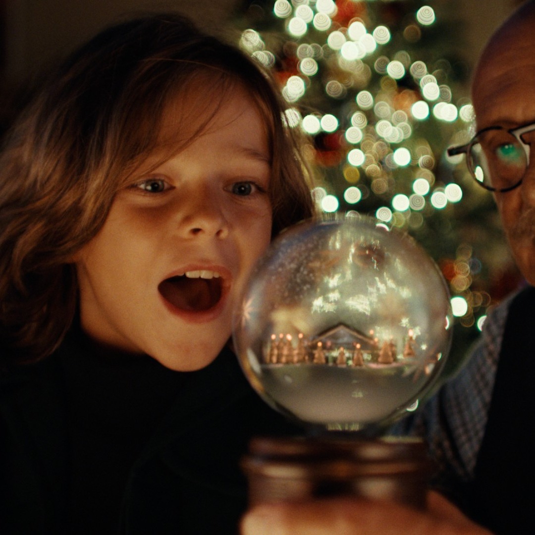 Un abuelo y su nievo miran una bola de Navidad