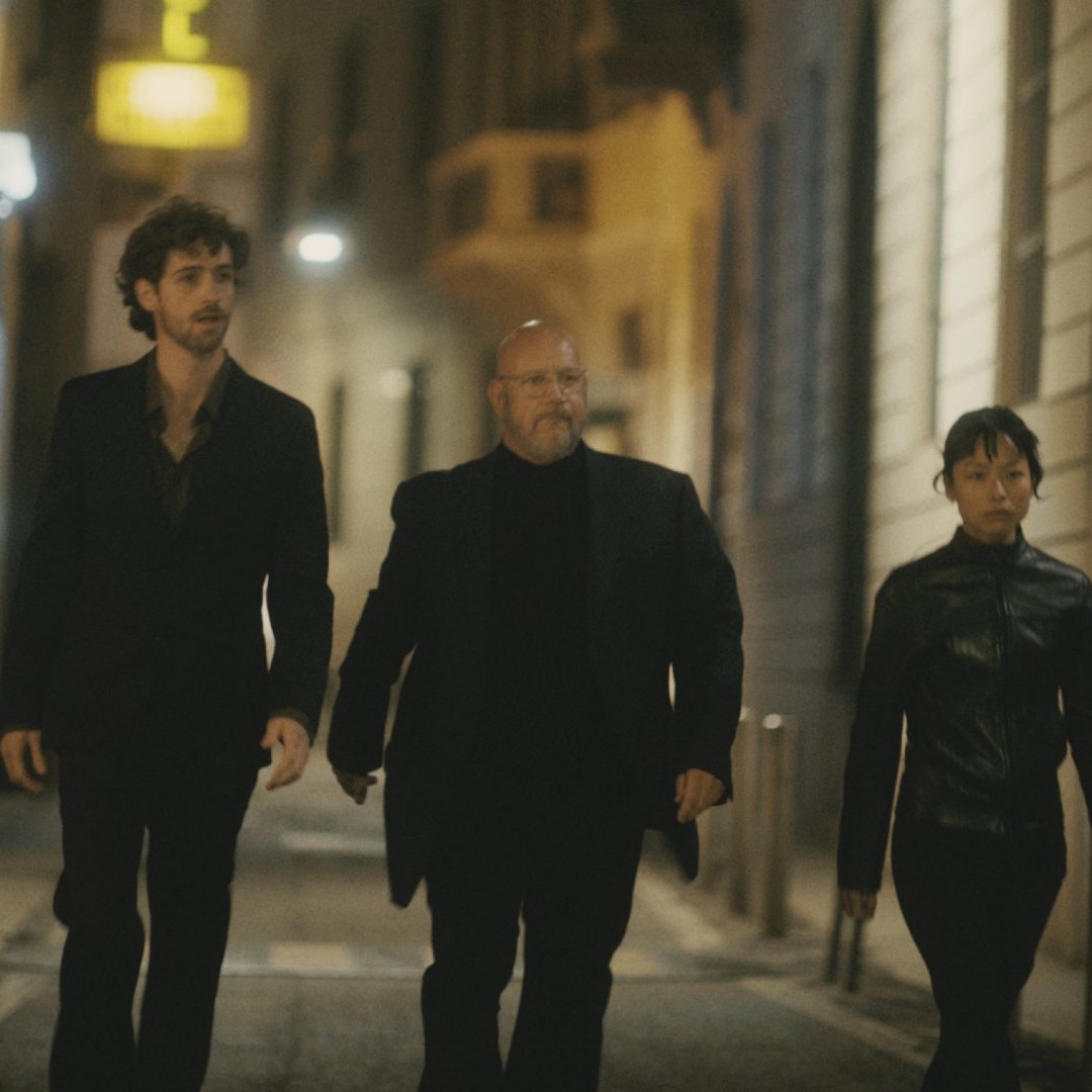 Tres personas vestidas de negro andando por la calle de noche