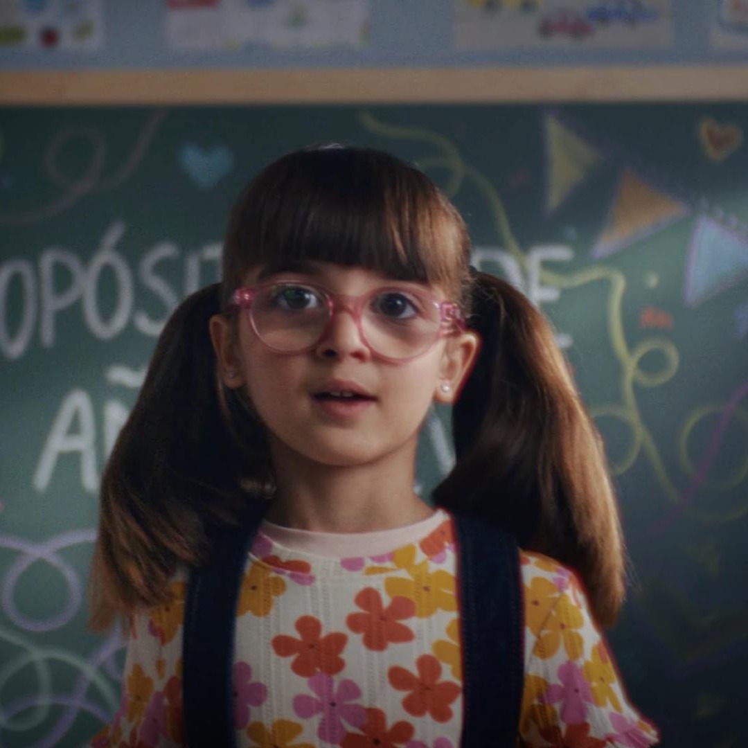 Niña con gafas delante de un pizarra