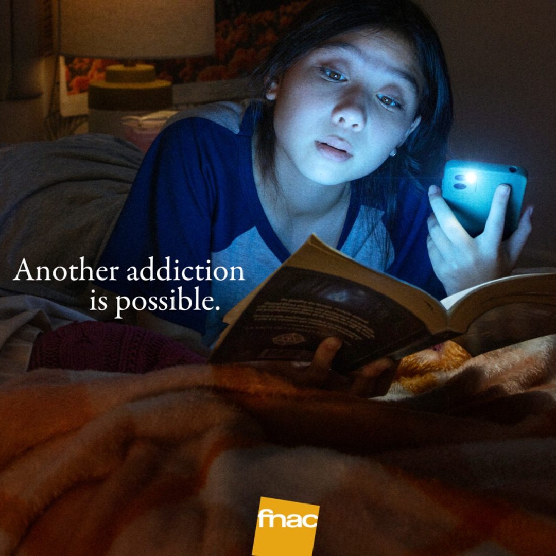 Joven lee un libro iluminado con la linterna del teléfono