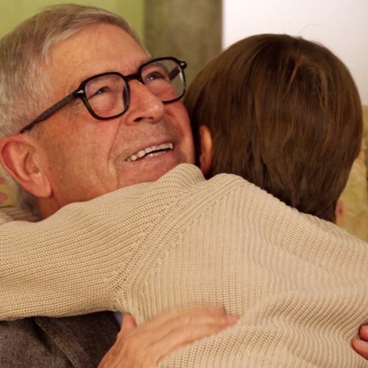 Un abuelo abrazando a su nieto pequeño en el sillón