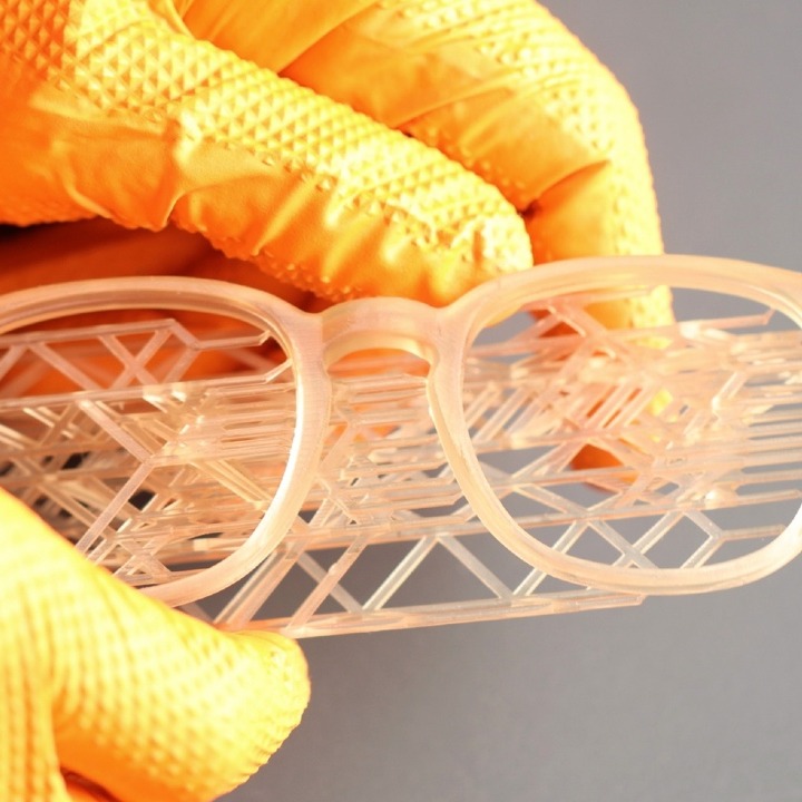 Unas manos con guantes sosteniendo unas gafas hechas en 3D