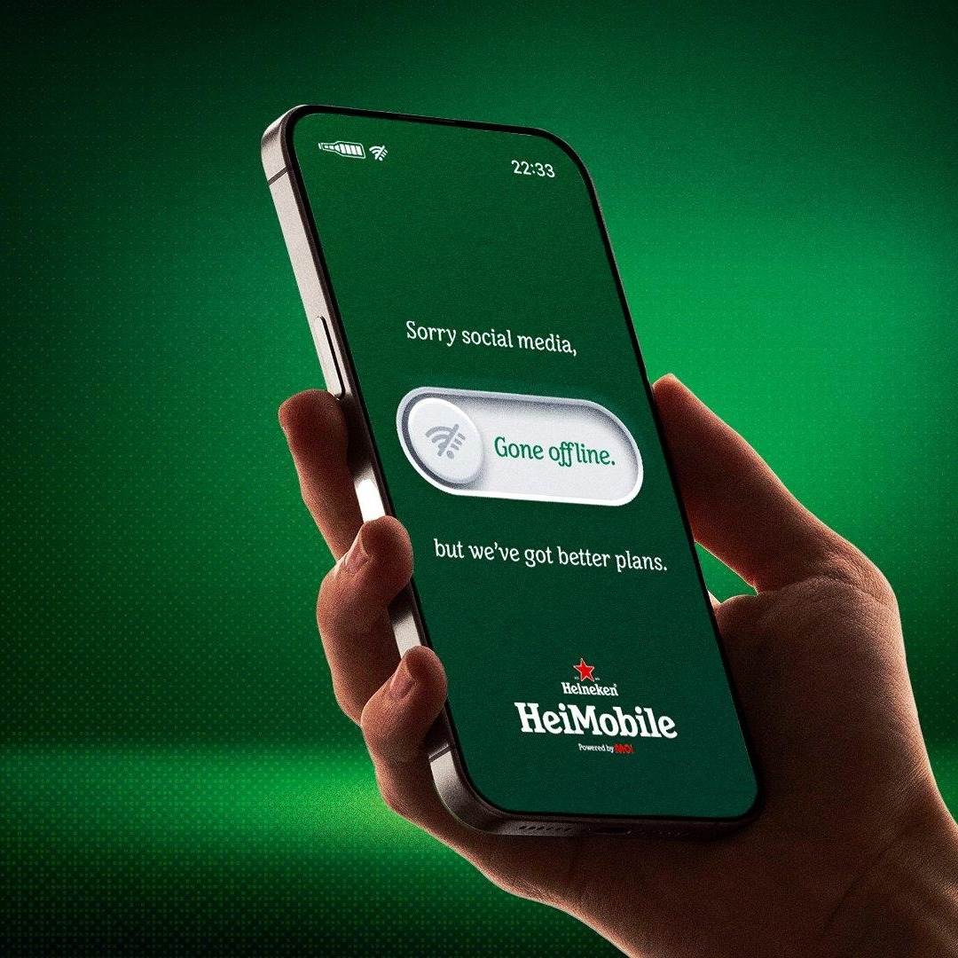 Mano sujetando un teléfono móvil con un mensaje de Heineken