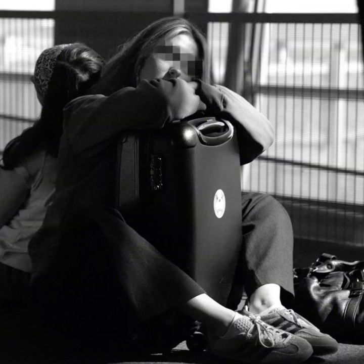 dos chicas durmiendo en el suelo del aeropuerto con las maletas