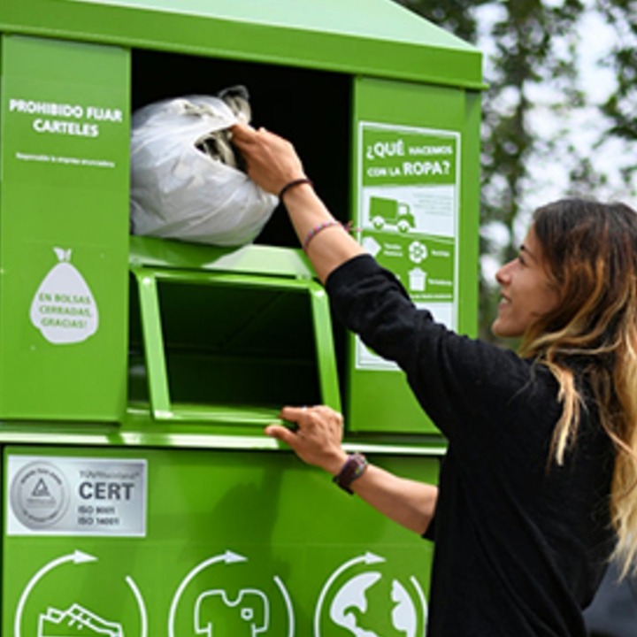 Una mujer depositando una bolsa de ropa en un contenedor de Humana