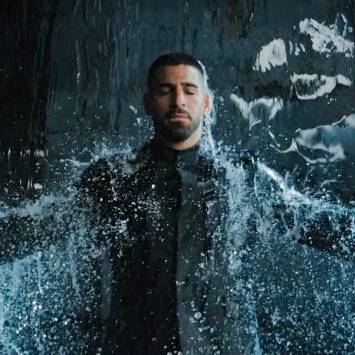 Adolfo Domínguez elige a Ilia Topuria como embajador para comunicar que es “Impermeable” Ilia Topuria con los brazos en cruz bajo una cortina de agua vestido