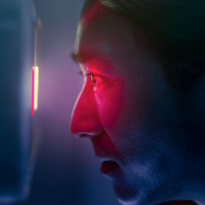 Un hombre mirando por una mirilla digital con luz roja
