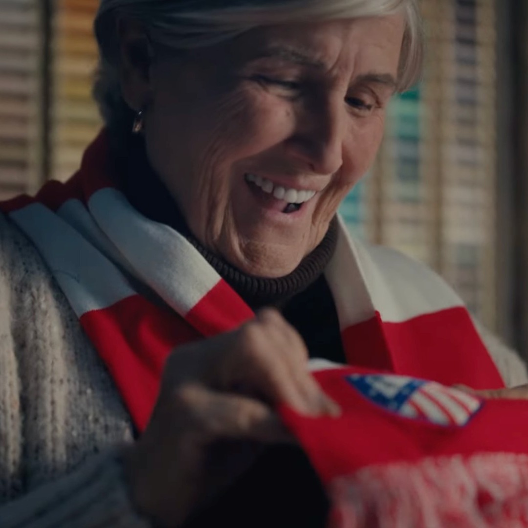 Mujer alegre al recibir una bufanda del Atlético de Madrid