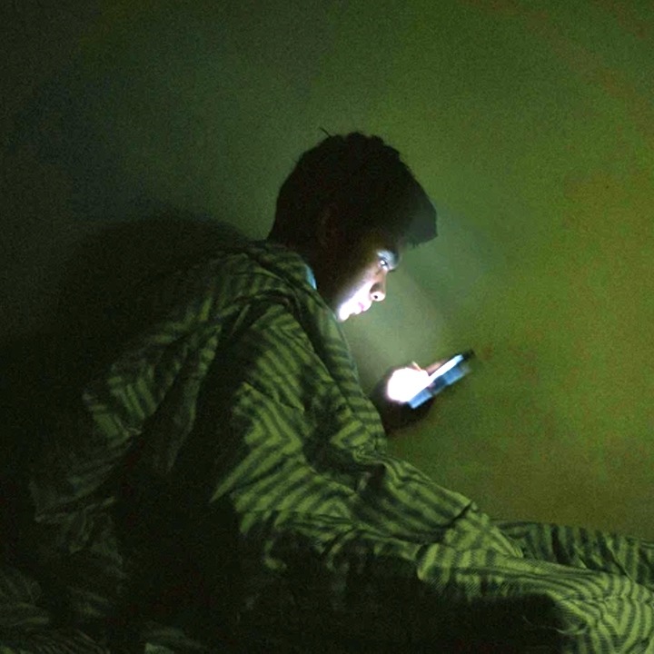 Un niño mirando el móvil en la cama a oscuras