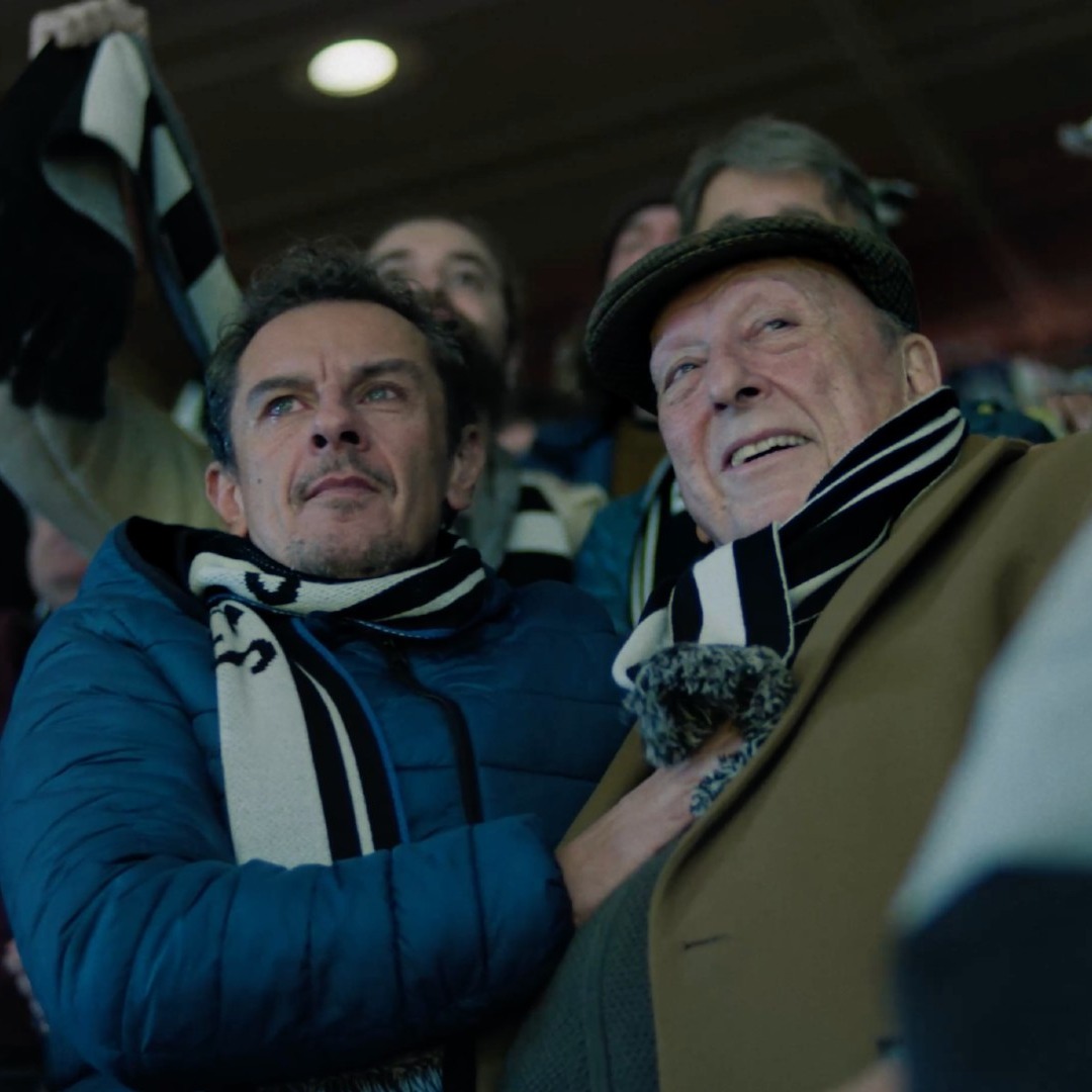 Un padre y un hijo viendo un partido de fútbol en un estadio
