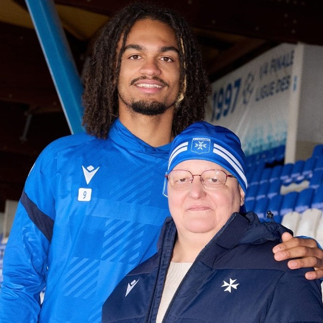 Dos futbolistas posando con enfermas de cáncer que llevan los gorros de color a juego con la equipación de su equipo