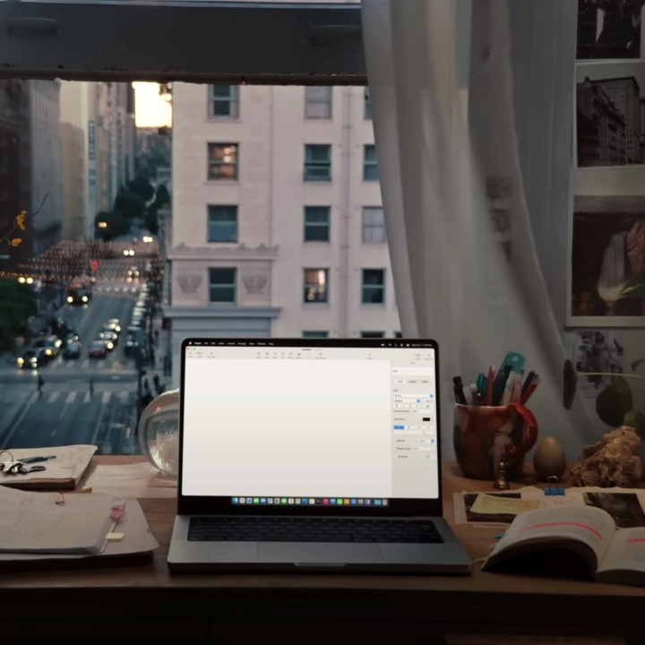 un escritorio de una casa con un Mac encendido y vistas a las calles de Nueva York por la ventana