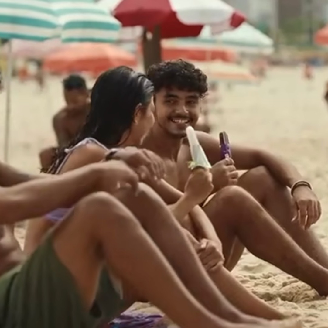 Tres personas jóvenes comen helado en una playa