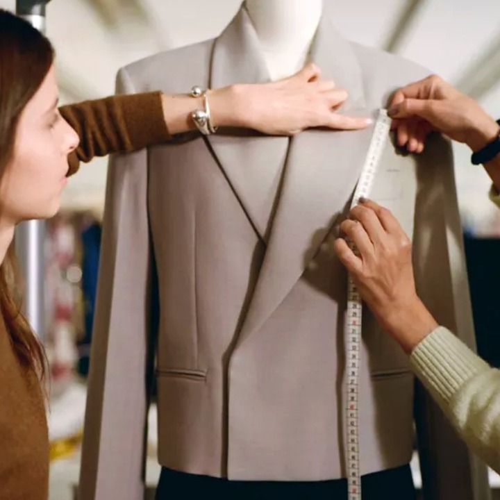 Dos mujeres tomando medidas a una americana colocada en un maniquí