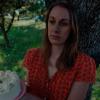 una mujer con cara triste sujeta una tarta de cumpleaños con una bengala encendida