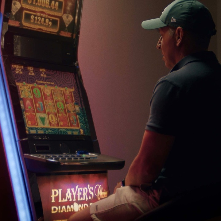 Un señor sentado jugando en una máquina tragaperras