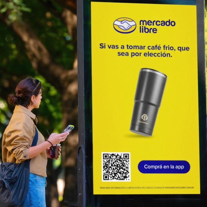 Una chica se detiene ante el mupi de Mercado Libre para leer el mensaje