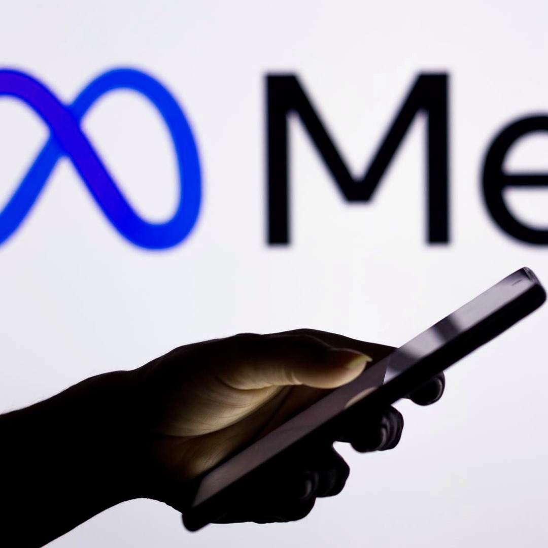 Mano sujetando un móvil con el logo de Meta detrás