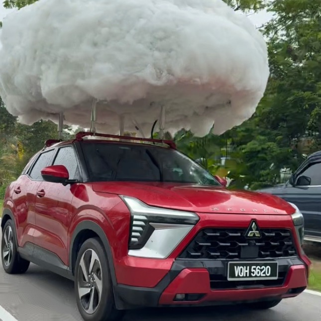 El coche rojo de Mitsubishi con una nube instalada encima de la que sale agua